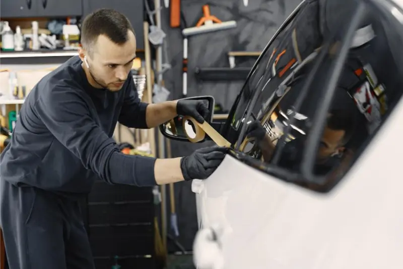 Technician working on a car door glass and mirror